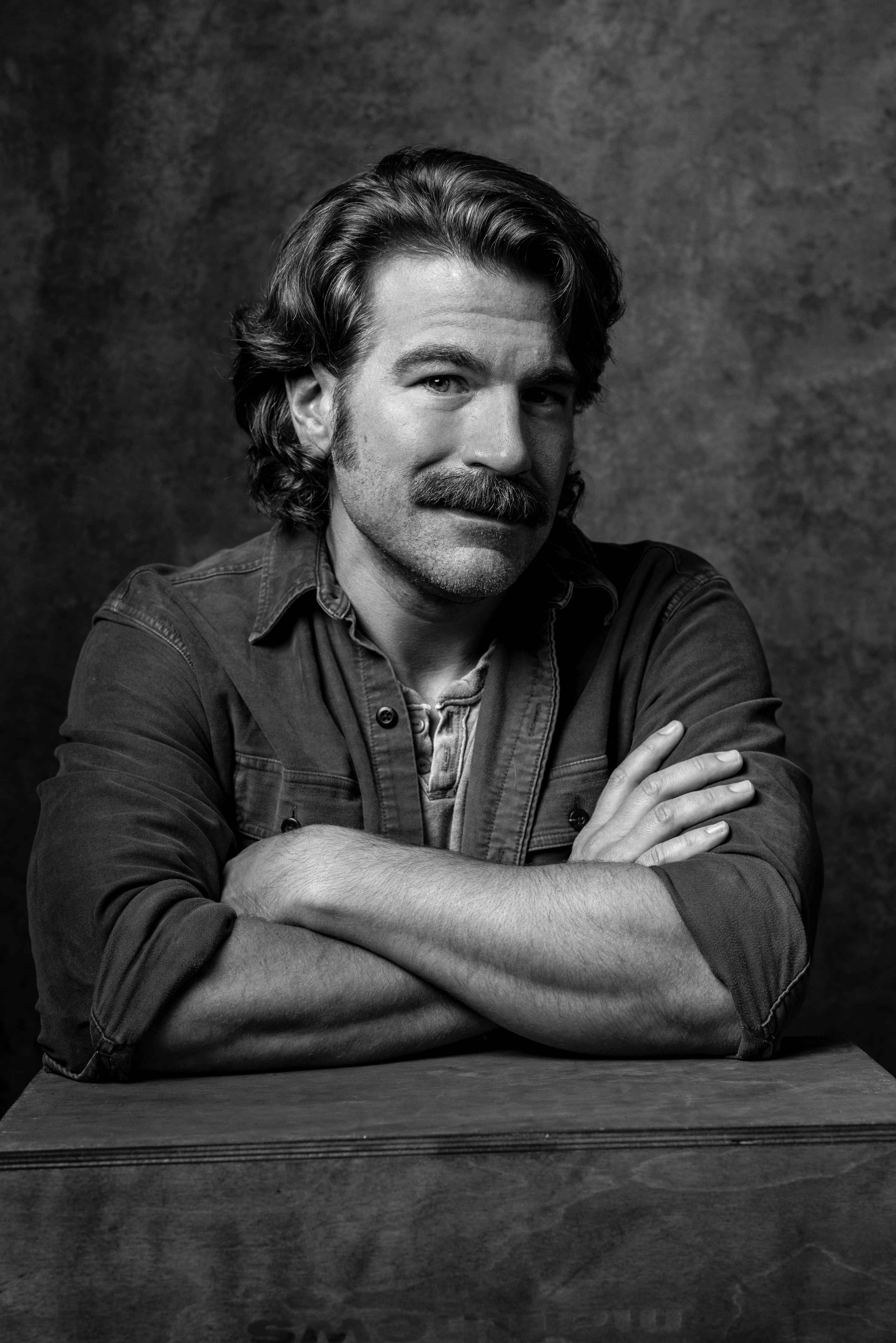 Burt Rutherford, leaning forward with his arms folded and a slight smile.